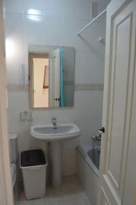 La salle de bains blanche est pourvue d'un lavabo et d'un miroir. dans l'établissement Precioso ático a pie de playa, en Miño., à Miño