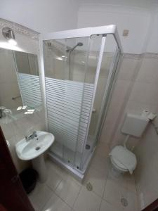 a bathroom with a shower and a toilet and a sink at DBV Guesthouse in Lagos