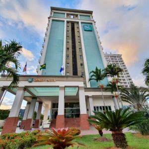 un edificio alto con palmeras delante en Quality Rio de Janeiro - Barra da Tijuca en Río de Janeiro