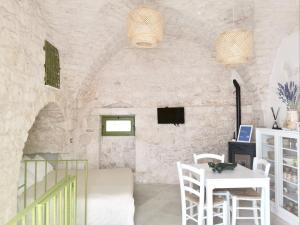uma sala de estar com uma mesa e cadeiras brancas e uma parede de pedra em Il Piccolo Frantoio em Ostuni