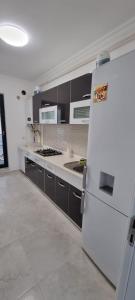 Il comprend une cuisine équipée d'un réfrigérateur blanc et de placards noirs. dans l'établissement Apartament 2 camere cu 2 bai Mamaia Butoaie, à Mamaia