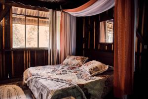 a bedroom with a bed with pillows and a window at Chalé Itape in Guabiruba
