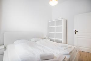 een witte slaapkamer met een wit bed met witte kussens bij Cottageviertel - Stilvolles Apartment in Parknähe in Wenen