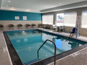 avid hotels - Chicago O Hare - Des Plaines في ديس بلينز: مسبح كبير مع كراسي وطاولات