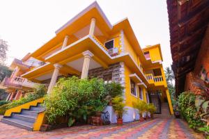 ein gelbes Gebäude mit Treppen und Pflanzen davor in der Unterkunft PINNACLE MIST , CALANGUTE BEACH ROAD in Calangute