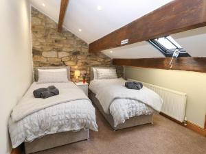 two beds in a room with a stone wall at Greenfield Cottage in Oakworth