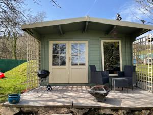a small green house with a grill and chairs at Ty Bach Twt, Coity Bach in Brecon