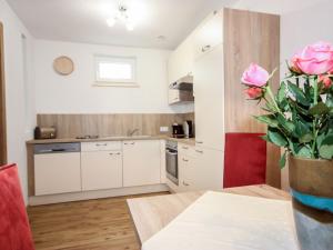 une cuisine avec des placards blancs et une table avec un vase de roses dans l'établissement Apartment Matilda by Interhome, à Ried im Oberinntal