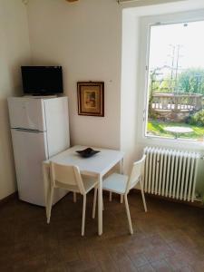 una mesa y sillas blancas con nevera y ventana en Nora Casa Vacanze, en Dervio
