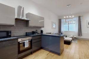 a kitchen with stainless steel appliances and a living room at Lovely 2 Bedroom Apartment near Highgate Station in London