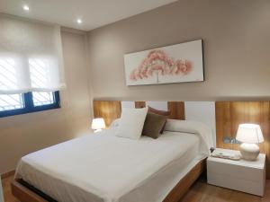 a bedroom with a white bed with a tree painting on the wall at Duplex Premium Peñiscola Playa Orangecosta in Peñíscola +25 photos
