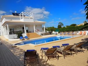 a villa with a swimming pool in front of a house at Sunset Villa by Laranjal Rentals in Olhos de Água