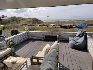 a deck with a view of the beach and cars at Ons Strandhuis in IJmuiden