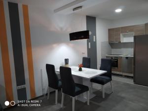 a kitchen with a white table and black chairs at Markaz Apartman Bihać 2 in Bihać +7 photos