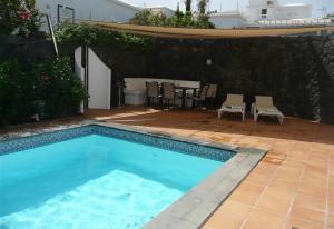 een zwembad in een tuin met een tafel en stoelen bij Villa Loretta in Puerto del Carmen