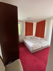een slaapkamer met een wit bed en rode loper bij Hotel Houštka in Brandýs nad Labem-Stará Boleslav