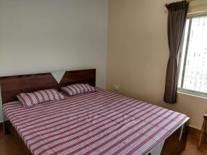 a bedroom with a bed with striped sheets and a window at Ashiyana Rest House in Deoghar