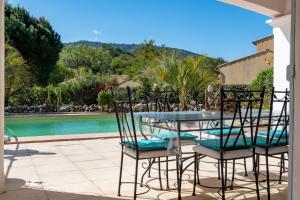 a glass table and chairs on a patio with a pool at Les Vergers in Gonfaron