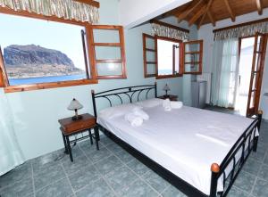 ein Schlafzimmer mit einem Bett und zwei Fenstern in der Unterkunft AGNANTIO in Monemvasia + 71 Fotos