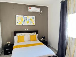 a bedroom with a bed with yellow pillows at Studio de haut standing, Bonamoussadi (Kotto) in Douala