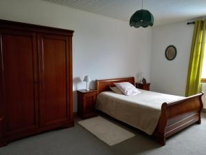 a bedroom with a bed and a wooden cabinet at LE LOGIS DE L'ETORE in Saint-Jean-dʼAngély