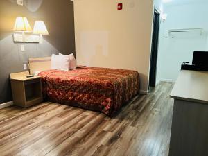 a hotel room with a bed and wooden floors at Regency Inn Tulsa in Tulsa