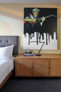ロサンゼルスにあるHotel Ziggy On Sunsetの銃を撃つ男の絵が飾られた寝室