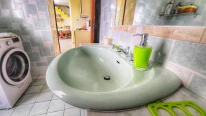 un lavabo verde en un baño con una bebida encima en Casa Nina, en Gonnesa