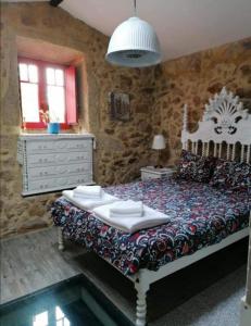 a bedroom with a bed and a stone wall at Moinho Azenha do campelo in Vila Verde
