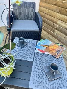 a table with two cups and a chair on a patio at Les Gîtes de Claire in Honfleur