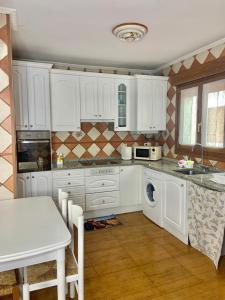 cocina con armarios blancos, mesa y fregadero en Apartamento La Herradura, en Villarcayo