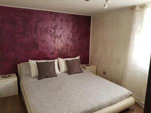sypialnia z łóżkiem z fioletową ścianą w obiekcie Casa Daniela w mieście San Felice Circeo