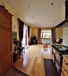 sala de estar con suelo de madera y cocina en Yellow Heights Country House, en Tinahely