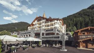 a large building with tables and umbrellas in front of it at Schlosshotel Ischgl 5-Sterne Superior in Ischgl