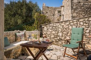 een patio met een tafel en een stoel op een stenen muur bij Traditional Stone House Anofli 1843 Fiskardo Kefalonia in Fiskardho