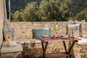 a wooden table on a balcony with at Traditional Stone House Anofli 1843 Fiskardo Kefalonia in Fiskardho