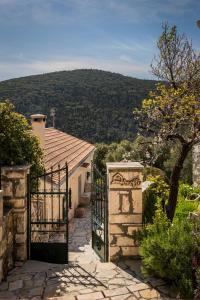 a gate to a house with a mountain in the background at Traditional Stone House Anofli 1843 Fiskardo Kefalonia in Fiskardho
