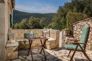 a patio with a table and chairs on a stone wall at Traditional Stone House Anofli 1843 Fiskardo Kefalonia in Fiskardho