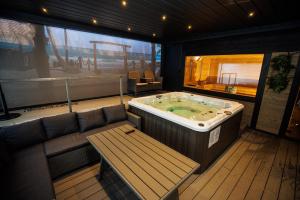 a jacuzzi tub in a room with a bench and a table at Arena Deluxe & Spa in Szeged