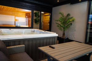 a bathroom with a tub and a table and a plant at Arena Deluxe & Spa in Szeged