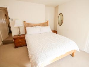Schlafzimmer mit einem weißen Bett und einem Spiegel in der Unterkunft Tudor Cottage in Conwy