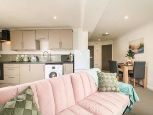 a living room with a couch and a kitchen at Lighthouse Lofts - St Anthony in Camborne