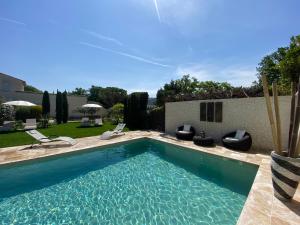 uma piscina num quintal com cadeiras e uma casa em Mas Beau Soleil & Spa Gîtes de Charme avec Jacuzzi Privé em Saint-Rémy-de-Provence