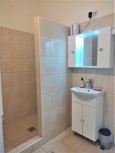 y baño con lavabo blanco y espejo. en Panoráma Apartman en Vác