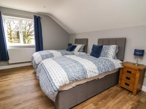 a bedroom with a bed with blue and white comforter and a window at Talarddu Cottage in Builth Wells