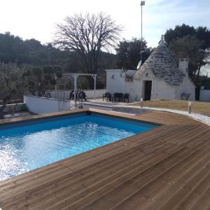 une piscine avec une terrasse en bois et un bâtiment dans l'établissement Villa Fransisca, à Alberobello