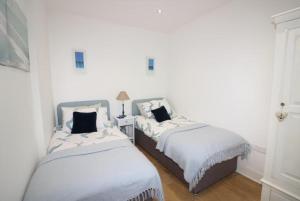 two beds in a room with white walls at Beachcomber Cottage in Troon