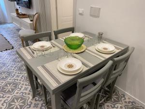 una mesa de comedor con platos y un tazón verde. en Suites 5 Stelle nel Borgo di Varazze, en Varazze