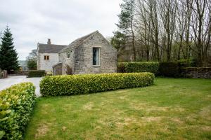 Brosterfield Cottage في Foolow: منزل حجري قديم مع ساحة خضراء