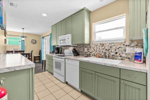 a kitchen with green cabinets and white appliances at Pier Watch in Flagler Beach